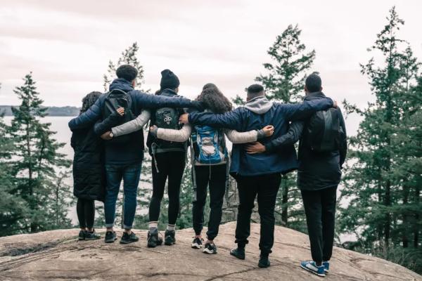 a photograph of a group of hikers hugging each other on a mountain