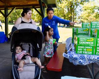 a photograph of Doris Castellanos showing people food boxes at the event